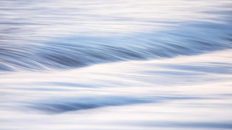 Long-exposure image of a water surface with soft blue and white streaks.