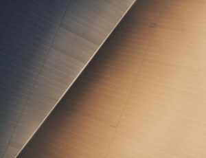 Close-up of angled metal panels forming a diagonal seam, with dark blue left side and warm beige right side.